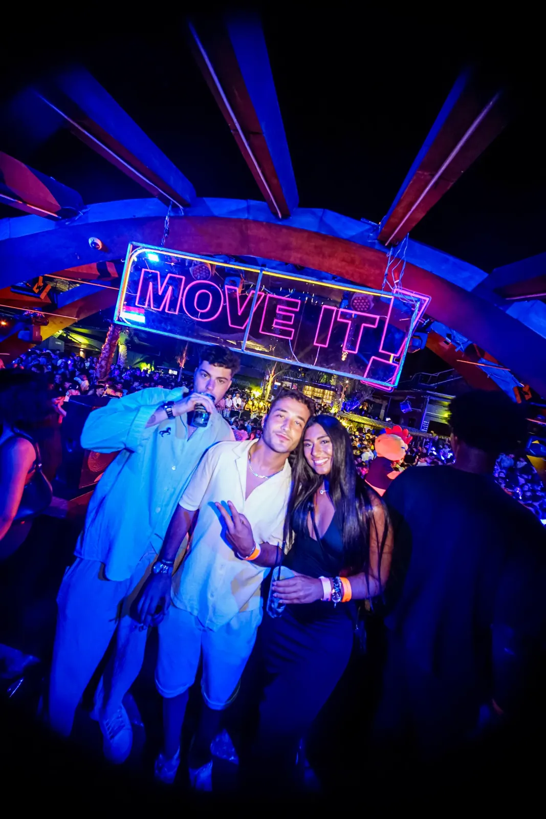 Friends posing in front of the neon Move it! sign